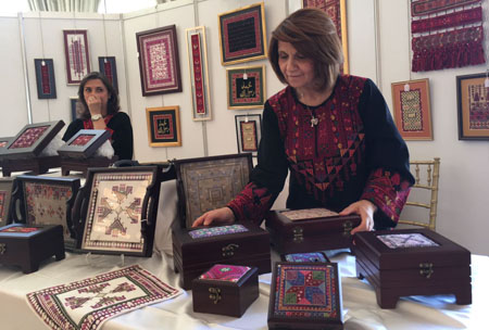 A woman arranges products inspired by Palestinian heritage at the Palestinian Cultural Exhibition in Amman on Saturday (Photo by Muath Freij)